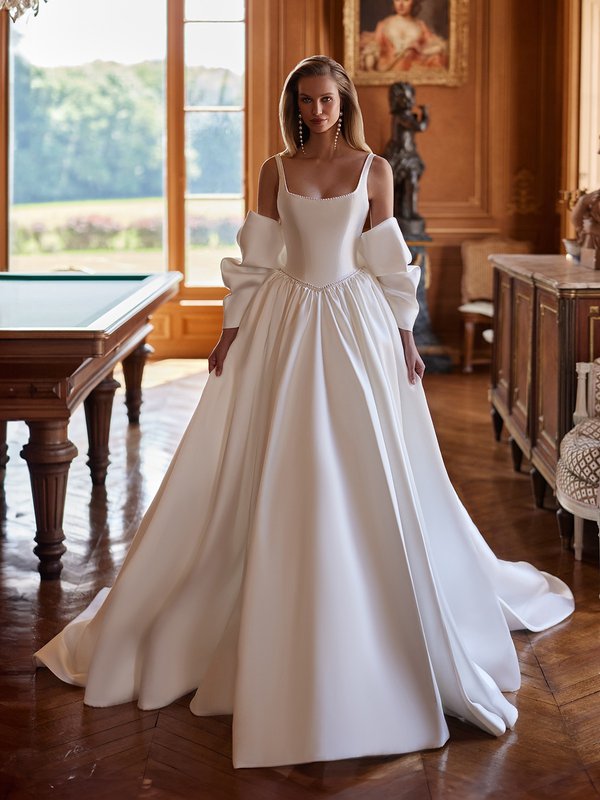 In a stunning room, the bride dazzles in a royal Mikado ball gown, featuring pearl accents and an optional bow shawl Moonlight Couture H1604