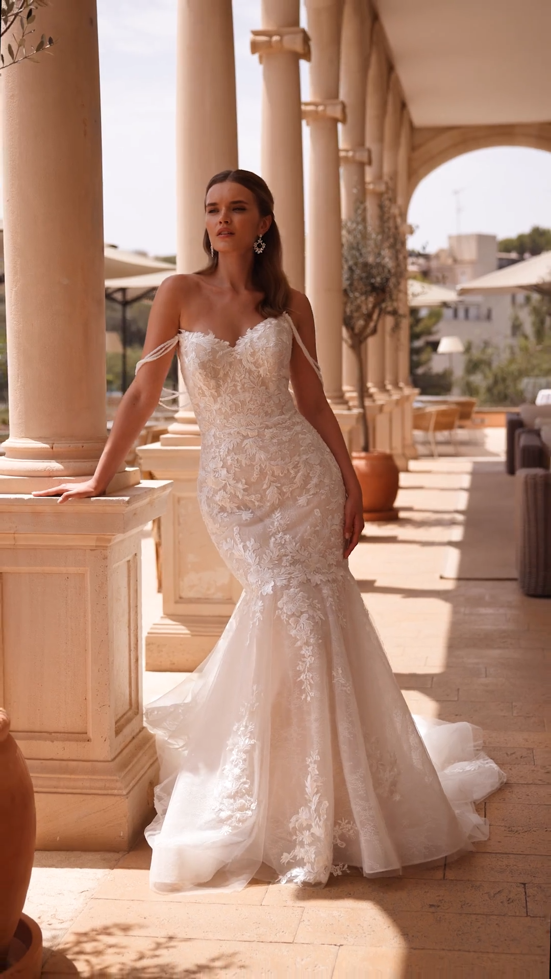 Bride wearing leaf lace wedding dress with cat eye neckline and detachable beaded strands